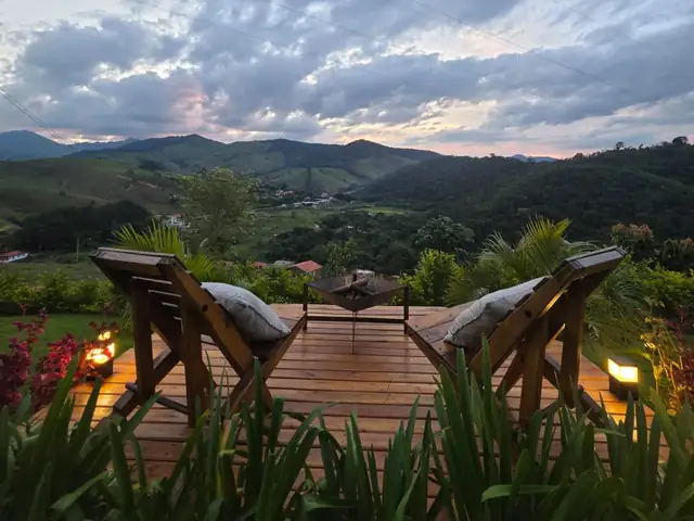 O deck com duas cadeiras de madeira e o fire pit, de frente para o vale ao entardecer