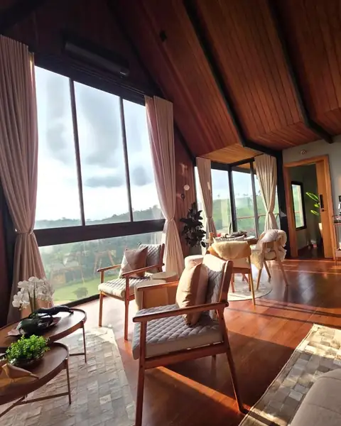 A sala com a janela grande aberta para a serra, durante o dia