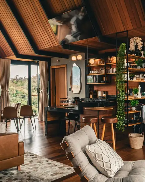 A sala e a cozinha sob o telhado de madeira, com a janela aberta para a serra