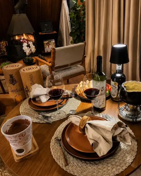 Mesa posta para dois com fondue, vinho e taças